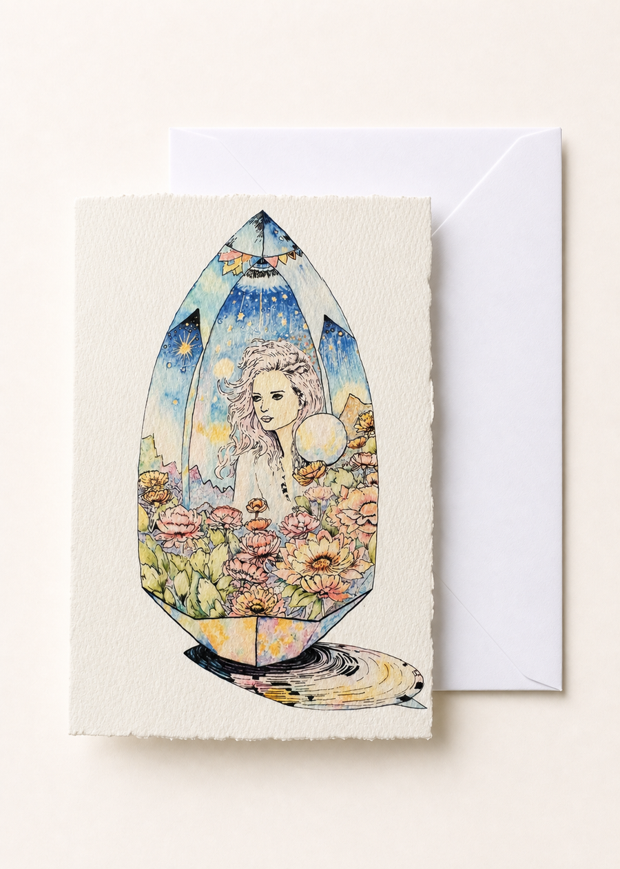 Amaréa 5x7 deckled-edge greeting card showing flower-crowned figure held inside a faceted gem with a white envelope