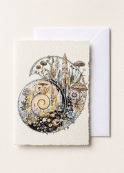 Ammonitae 5x7 deckled-edge greeting card showing ammonite spiral filled with crystals, fossils, flowers, and fungi with a white envelope