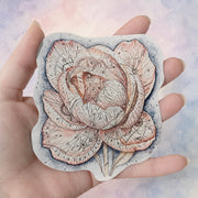 Hand holding the Atlas in Bloom botanical sticker on a pastel watercolor background for scale